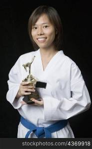 Portrait of a young woman holding a trophy and smiling