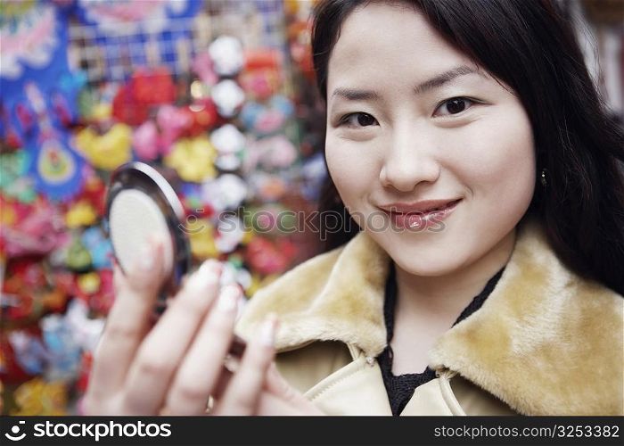 Portrait of a young woman holding a vanity mirror