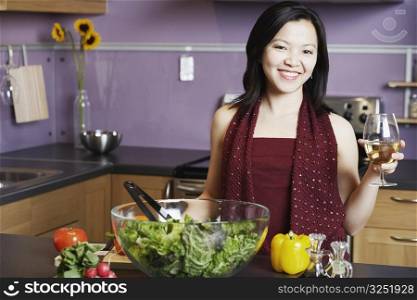 Portrait of a young woman holding a wineglass smiling in the kitchen