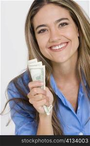 Portrait of a young woman holding American paper currency and smiling