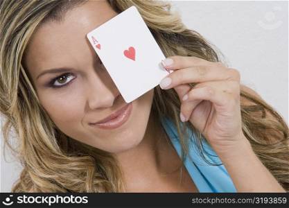 Portrait of a young woman holding an ace card and smiling