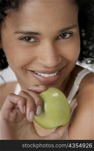 Portrait of a young woman holding an apple and smiling