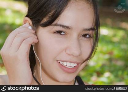 Portrait of a young woman holding an earbud and smiling