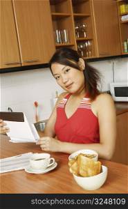 Portrait of a young woman holding an envelope at a kitchen counter
