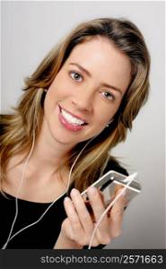 Portrait of a young woman holding an MP3 player and listening to music