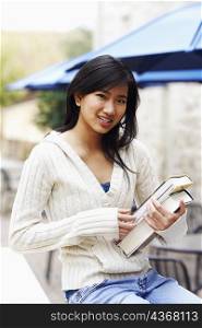 Portrait of a young woman holding books and smiling