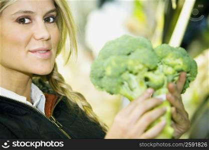 Portrait of a young woman holding broccoli