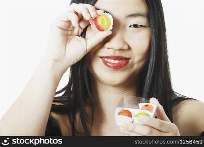 Portrait of a young woman holding candy in front of her eye