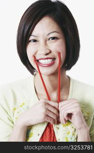 Portrait of a young woman holding chopsticks