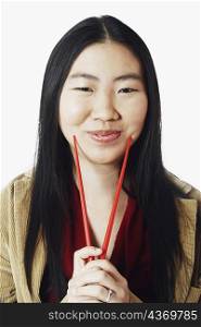 Portrait of a young woman holding chopsticks and smiling