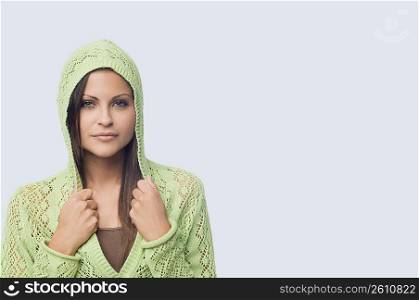 Portrait of a young woman holding collars of her hooded shirt
