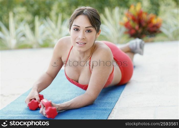 Portrait of a young woman holding dumbbells on an exercise mat