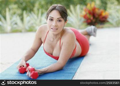 Portrait of a young woman holding dumbbells on an exercise mat