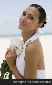 Portrait of a young woman holding flowers on the beach