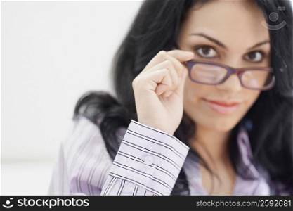 Portrait of a young woman holding her eyeglasses