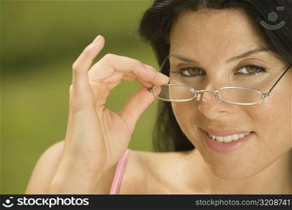 Portrait of a young woman holding her eyeglasses