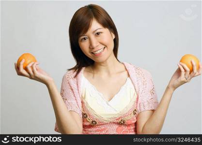 Portrait of a young woman holding oranges