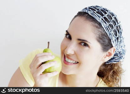 Portrait of a young woman holding pear and smiling