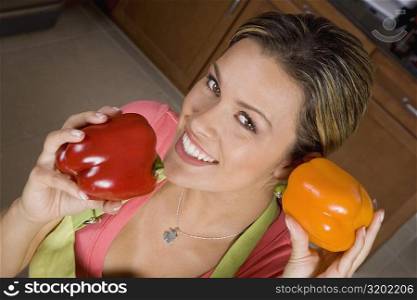 Portrait of a young woman holding red and yellow bell peppers and smiling