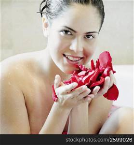 Portrait of a young woman holding rose petals and smiling