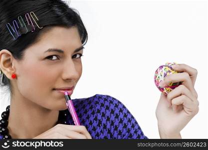 Portrait of a young woman holding rubber bands and a pen