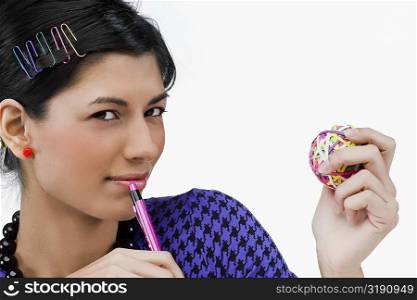 Portrait of a young woman holding rubber bands and a pen