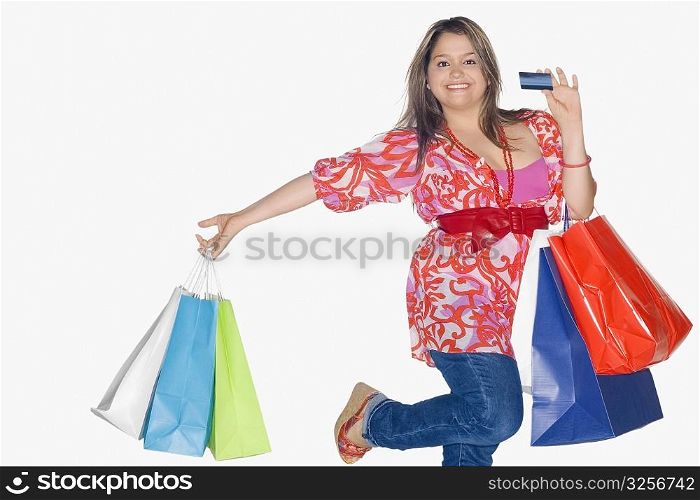 Portrait of a young woman holding shopping bags and dancing