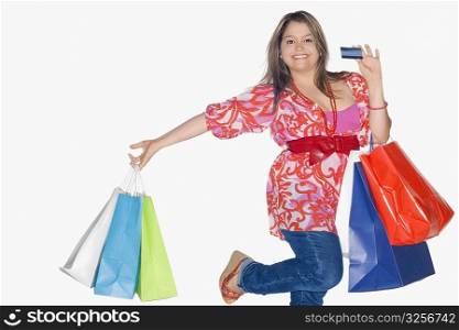Portrait of a young woman holding shopping bags and dancing