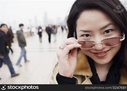 Portrait of a young woman holding sunglasses over her eyes