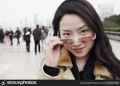 Portrait of a young woman holding sunglasses over her eyes
