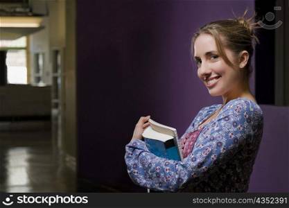Portrait of a young woman holding textbooks and smiling