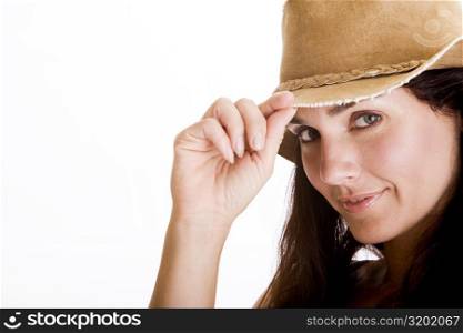 Portrait of a young woman holding the tip of her hat