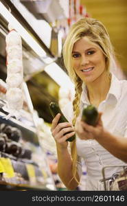 Portrait of a young woman holding two cucumbers and smiling