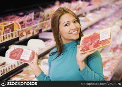 Portrait of a young woman holding two packets in a supermarket and smiling