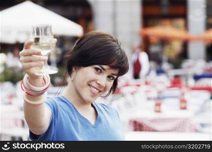 Portrait of a young woman holding up a glass of white wine