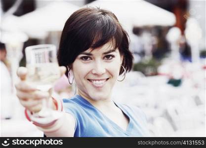 Portrait of a young woman holding up a glass of white wine