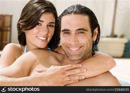 Portrait of a young woman hugging a mid adult man from behind