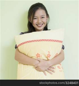 Portrait of a young woman hugging a pillow and smiling
