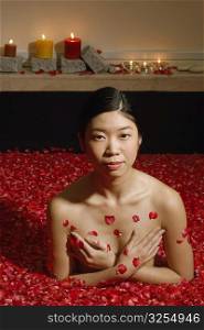 Portrait of a young woman in a bathtub full of rose petals