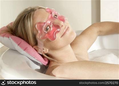 Portrait of a young woman in a bathtub wearing an eye mask