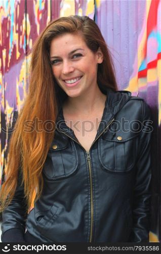 Portrait of a young woman in front of a colorful wall.