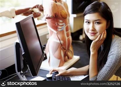 Portrait of a young woman in front of a computer and an anatomical model