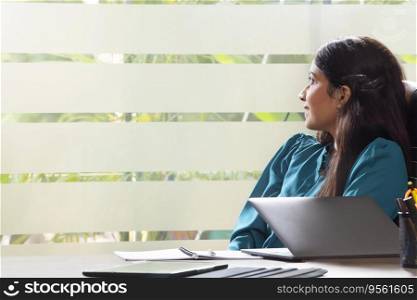 PORTRAIT OF A YOUNG WOMAN IN OFFICE LOOKING OUTSIDE AND THINKING