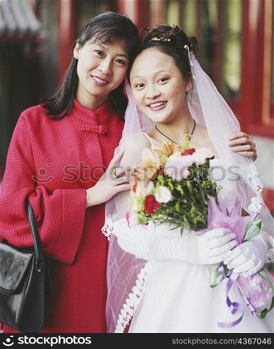Portrait of a young woman in the wedding dress posing with another woman