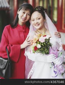 Portrait of a young woman in the wedding dress posing with another woman
