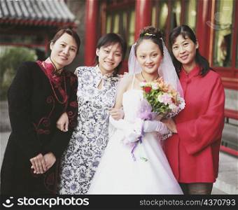 Portrait of a young woman in the wedding dress posing with three young women