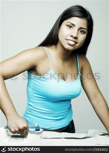 Portrait of a young woman ironing a shirt and smiling