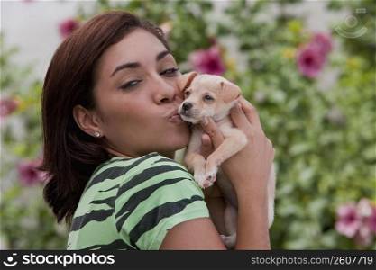 Portrait of a young woman kissing a puppy