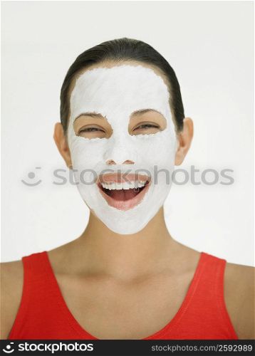 Portrait of a young woman laughing with a facial mask on her face