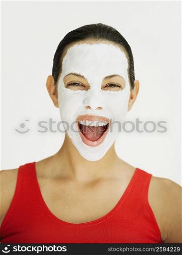Portrait of a young woman laughing with a facial mask on her face